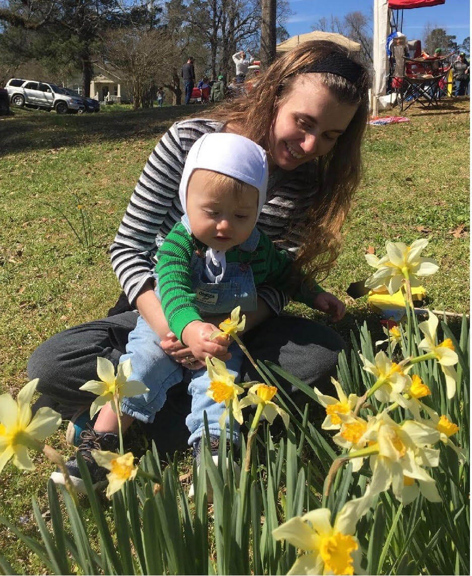 mommy sitting with baby around flowers